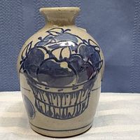 Front view of the 4.5 inch salt glazed stoneware jug showing hand-painted blue basket of fruit design