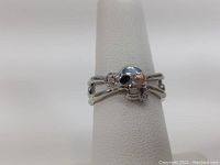 Front angled view of sterling silver skull ring on display stand showing skull and heart detail.