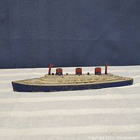 Side view of the small metal toy ship showing overall shape and paint scheme.