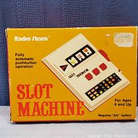 Photo of the original yellow box for the Radio Shack slot machine showing image and features text.