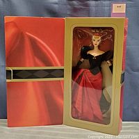Front and partially open box showing Winter Splendor Barbie doll in red skirt and black top with puffed sleeves.