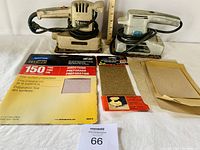 Photo showing both sanders, sandpaper sheets including a 150 grit sheet and smaller sheets, with measuring stick to show size.
