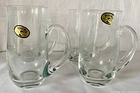 Four clear crystal beer steins with handles displayed in a row, all bearing the original Bohemia Crystalex Czechoslovakia stickers on the upper side.