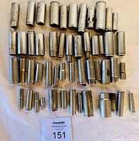 Top-down view of over 50 long sockets arranged in rows on a light surface, showing various sizes and signs of wear.