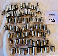 Photo showing multiple short length sockets of various sizes arranged on a surface, some showing wear and dirt.