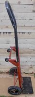 Older hand cart with black curved handle and visible red metal frame with wheels.