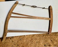 Antique cross cut wooden buck/bow saw on carpet showing wood grain and metal blade teeth
