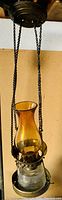 Full view of the antique hanging coal oil lamp showing the amber glass chimney, brass casing, and hanging chains.