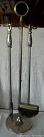 Vintage heavy brass fireplace tool set including stand, poker, and brush, shown against a white backdrop.