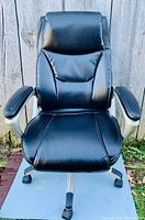 Front view of black leather office chair showing padded seat, high backrest and armrests.