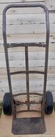 Front view of vertical metal hand cart dolly showing frame, handle, and tires.