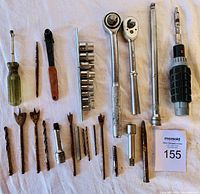 Overview of all tools laid out on a white surface, showing ratchets, socket extensions, screwdrivers, drill bits, and socket set.