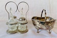 Front view of the vintage cruet condiment set with metal carrier and glass containers paired with the silver plated footed bowl showing overall appearance and condition.