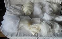 White lace and sheer cotton fabric folded and rolled on a table.