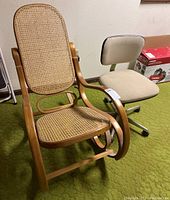 Side view of vintage bentwood rocking chair and beige rolling office chair on green carpet.