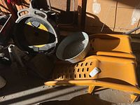 Two yellow plastic car ramps, metal oil drain pan, and black oil recovery container in garage setting.