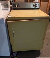 Front view of yellow vintage General Electric clothes dryer showing door and overall condition.