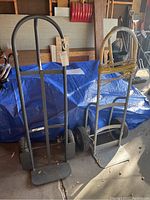 Wide view of two handcarts showing their frames, handles, and tires in a garage setting.