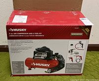 Front of sealed Husky 2 gal air compressor and 4-tool kit box showing product image and branding