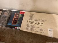 Photo showing detailed measurements and features of the bookshelf on the packaging box.