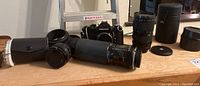 Image showing Nikkormat camera and multiple lenses aligned on surface