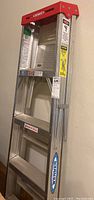 Full view of Werner aluminum step ladder showing red top and aluminum steps and rails with Werner branding.