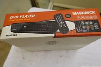 Magnavox MDV2100 DVD Player original box showing product image, brand, model number and icons illustrating key features.