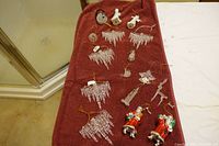 Lot of various Christmas ornaments including icicles, snowmen, Santa Claus figurines, reindeer and angel on red towel.