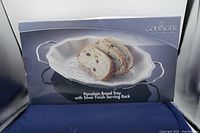 Front view of the Godinger porcelain bread tray with silver finish serving rack, showing box with bread slices on the tray image.
