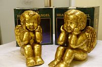 Two gold tone angel figurines in front of their boxes marked 'Heavenly Angel'