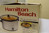 Box and front view of Hamilton Beach slow cooker showing brand, product image, capacity of 6 liters, and some features in Spanish.