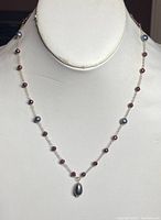 Front view of the full necklace on display, showing the alternating amethyst beads and cultured pearls along the gold chain with the central pearl pendant.