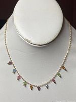 Front view of delicate gold chain necklace with small multi-colored drop stones on mannequin bust.