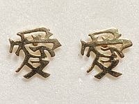 Front view of pair of small gold stud earrings shaped as Chinese symbols