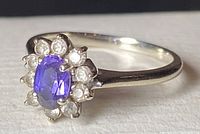 Close-up of ring face showing oval purple amethyst and halo of round diamonds