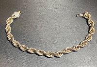 Full view of the thick silver rope chain bracelet laid flat showing length and style.