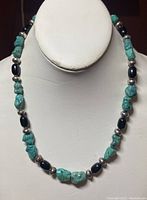 Necklace displayed straight on a white bust, showing turquoise, black beads, and silver spacers.