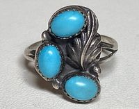 View of ring face showing three oval turquoise stones with leaf design in sterling silver.