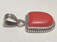 Close-up side view of the pendant showing the coral stone and silver bead border with the bail.