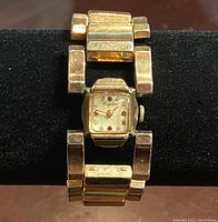 Full view of Kingston gold-filled vintage ladies wristwatch on black display stand showing watch face and linked bracelet.