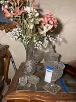 Single image showing all main items: pedestal vase with faux flowers, two crystal urns without lids, two small glass dishes.
