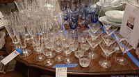 Overview shot showing the full assortment of clear and blue-tinted Japanese barware glasses with etched bamboo designs arranged on a wooden table.