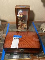 Jewelry box and butterfly music box side by side from front view, showing wood grain and glass panel