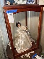 Porcelain bride doll inside wooden framed glass display case measuring 18x18x29 inches