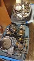 Overview of assorted silverplate trays, candle holders, and bowls stacked in bins showing tarnish and dirt