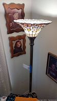 Full view of floor lamp showing stained glass type floral shade and metal stem and base.