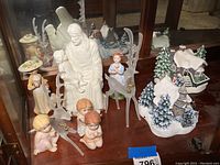 Display of all collectible figurines including the 3 angel figurines, 2 glass reindeer, and porcelain figures of a woman with hat, girl in dress, and male figure with child.