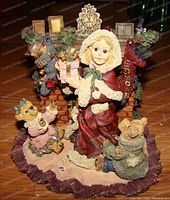 Front view of the Sandra Claus figurine showing the girl holding gifts in front of the fireplace with teddy bears and toy dragons.