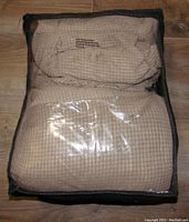 The gray sofa slipcover and cushion covers neatly folded inside a black mesh storage bag with plastic front window.