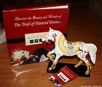 Photo showing the painted white Sundancer horse figurine with Plains Indians inspired artwork, alongside the original box and booklet.